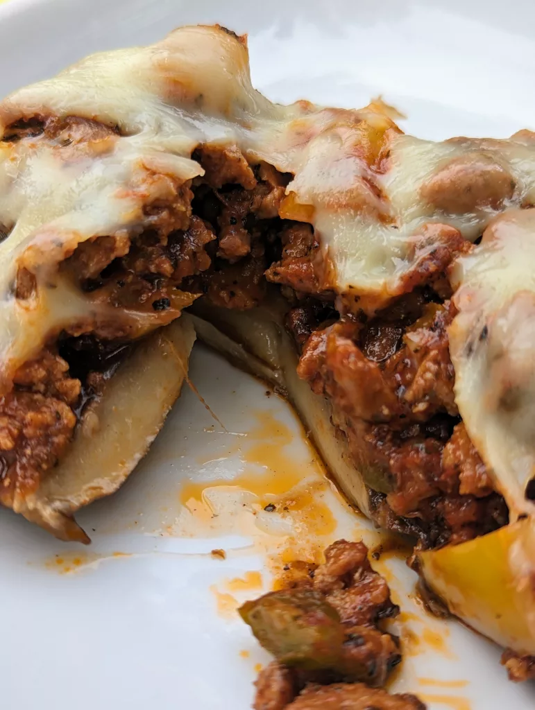 Stuffed portobello mushroom cut open to see the inside which is chorizo and peppers and topped with melted mozzarella cheese.