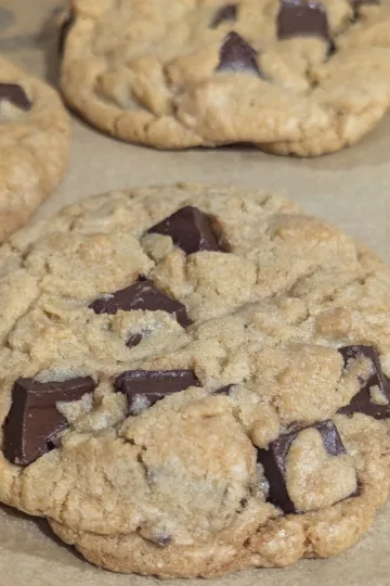 Three chocolate chunk cookies on parchment paper.