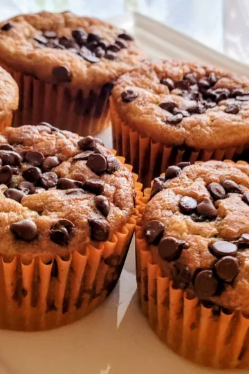 Six Chocolate chip pumpkin muffins in orange muffin papers.