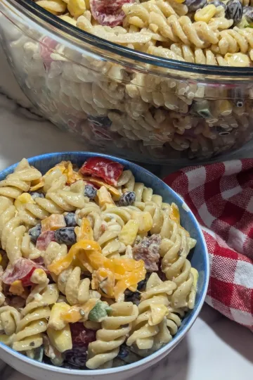 A small bowl of cowboy caviar pasta salad in front of a larger bowl.