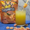 A glass of fuzzy peach mocktail with a bag of fuzzy peach candies in the back left side.