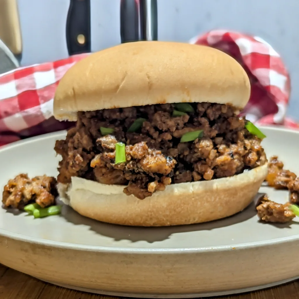 Hawaiian Loose Meat Sandwiches on a plate with a red and white checkered napkin in the back.