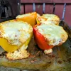 Four pizza stuffed peppers on a tray outside in front of a fence.