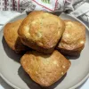 A plate of four apple cider muffins with three on the bottom and one on the top of them.
