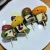 Four caprese salad skewers with balsamic reduction and olive oil over them.
