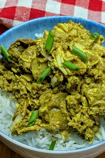 A bowl of curry chicken over rice.
