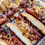 A tray of chili dogs covered in melted cheese.