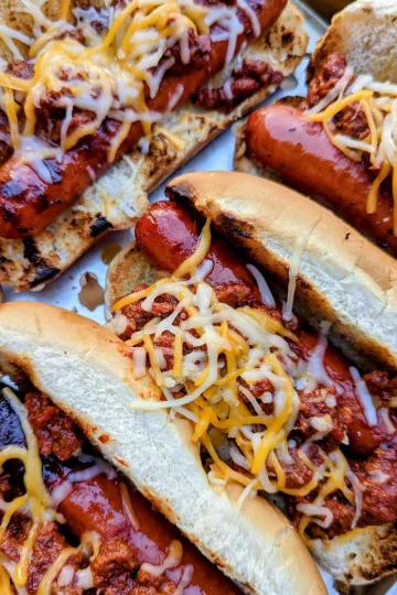 A tray of chili dogs covered in melted cheese.