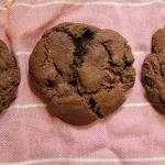 A Nesquik Chocolate Chip cookie on a pink and white cloth. Two more cookies can be barely seen off to both sides of the cookie.
