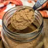 A spoon of pumpkin pie spice over a jar of spice.