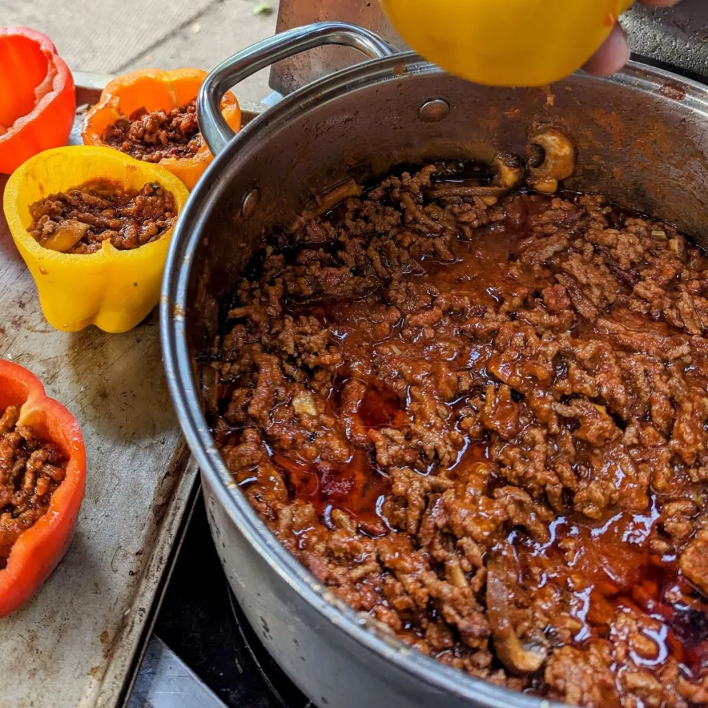 A pot of beefy pizza sauce with peppers beside it filled with sauce.