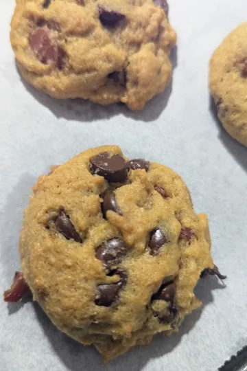 Three Bourbon bacon chocolate chip cookies on parchment paper lined cookie sheet.