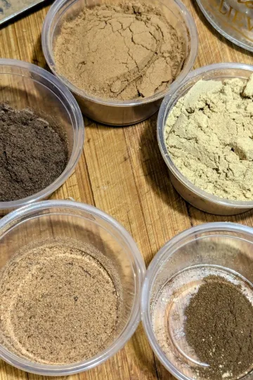 Small containers of spices to make gingerbread spice mix. Clockwise from the top: cinnamon, ginger, cloves, nutmeg, and all-spice.
