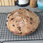 A loaf of No Knead Cinnamon Raisin Bread cooling on a wire rack.