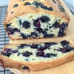Easy blueberry loaf sliced open on a wooden cutting board.