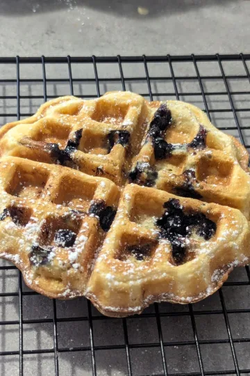 A blueberry waffle on a wire rack.