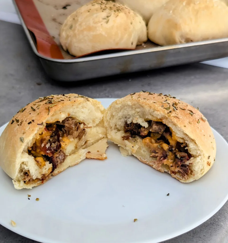 Brisket and Cheddar Pockets cut in half on a plate with more pockets in the background.