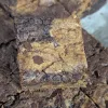A cut square of brownie chocolate chip cookie bars sitting on top of the rest of the pan of bars.