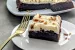 A square piece of Canadian Whisky Brownies on a white plate with a golden fork and the rest of the brownies in the background.