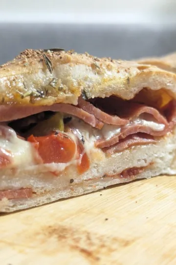Stromboli sliced open showing pepperoni and melted cheese on the inside.