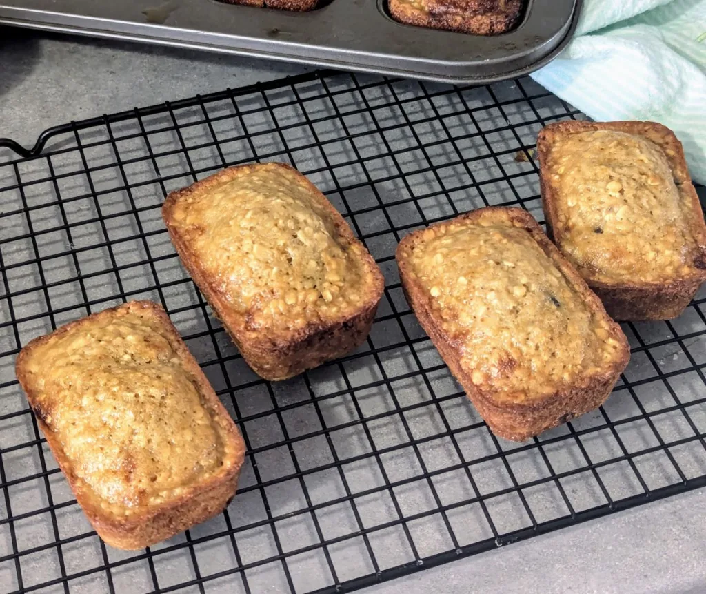 Four mini oatmeal loaves on a wire rack.
