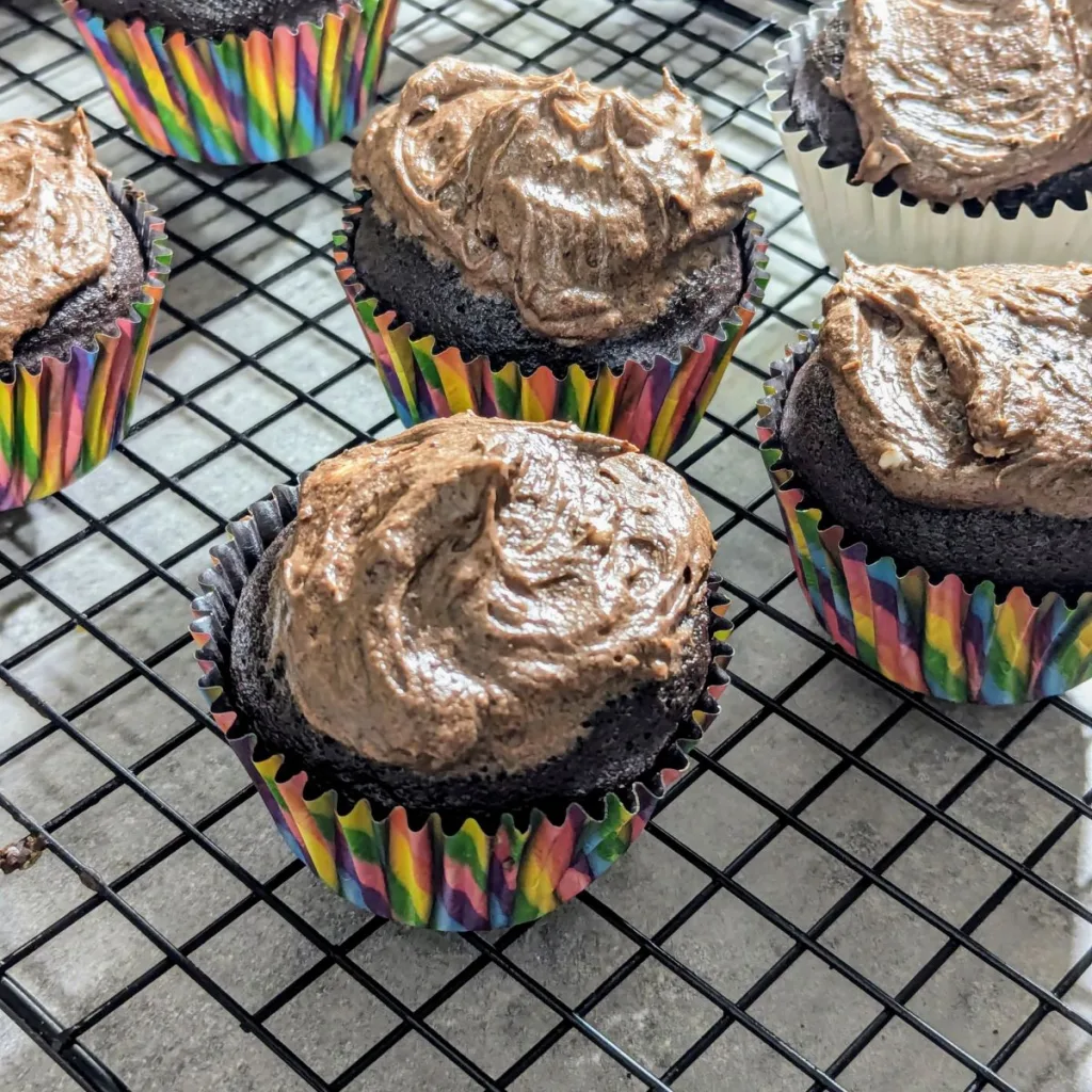 Chocolate cupcakes in rainbow wrappers with chocolate buttercream icing.
