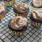 Chocolate cupcakes in rainbow wrappers with chocolate buttercream icing.