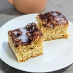 Two square pieces of Focaccia Style Cinnamon Buns on a white plate.