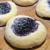 Blueberry filled kolaches dusted with powdered sugar on a wooden board.