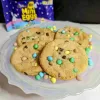 A plate with four mini egg cookies and a bag of mini eggs in the background.