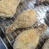 Two chicken drumsticks with homemade shake and bake on them on a wire rack.
