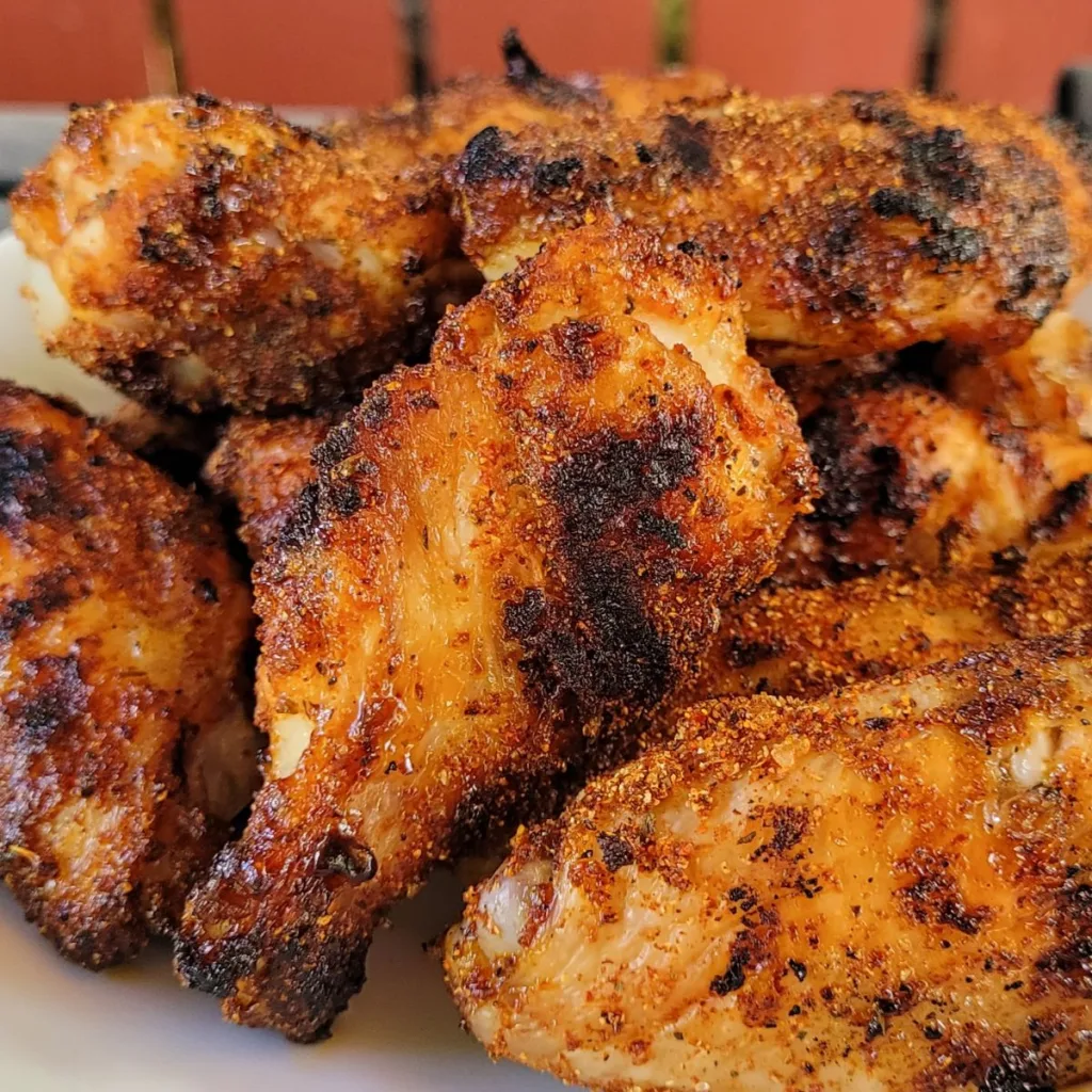 Dry rub chicken wings piled on a plate.