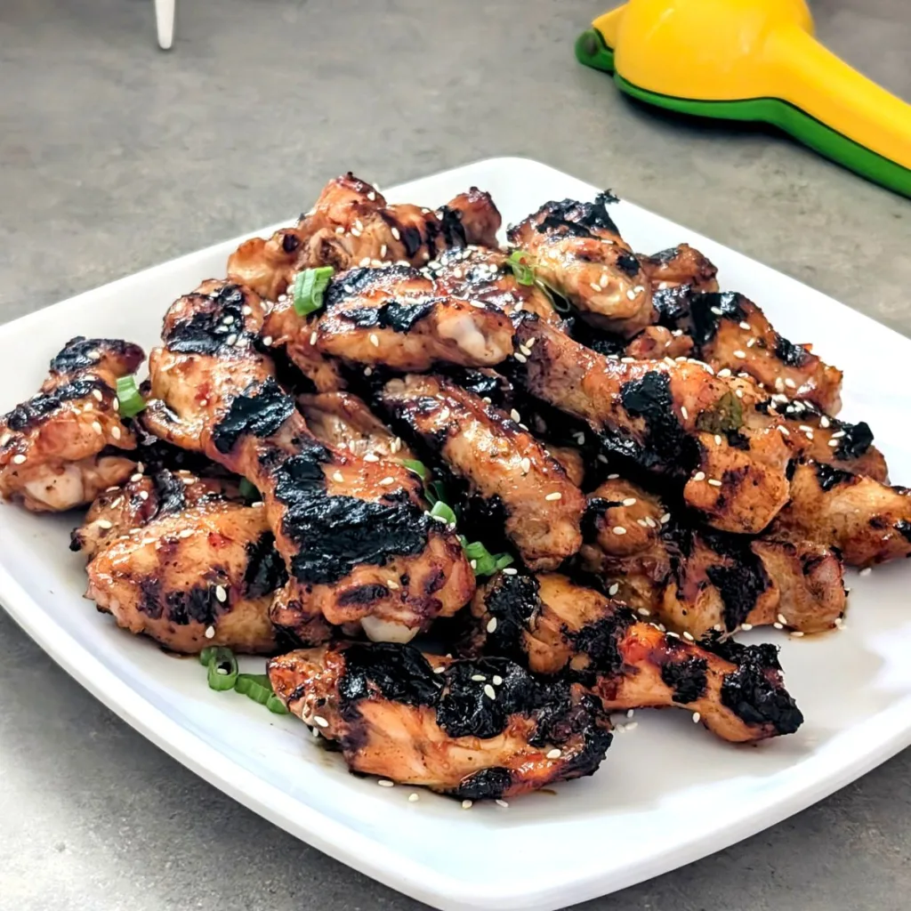 A square white plate with a pile of chicken wings.