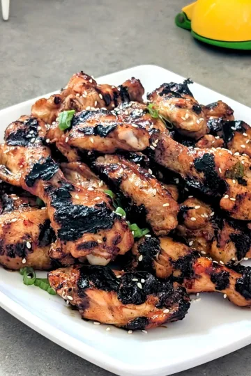 A square white plate with a pile of chicken wings.