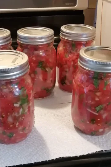 Five jars of homemade salsa on white paper towels.