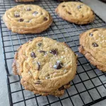 Four salted chocolate chip cookies on a wire cooling rack.