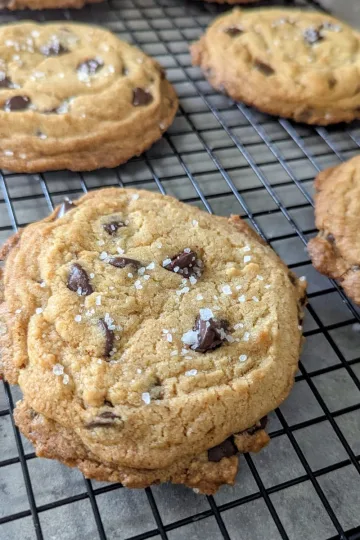 Four salted chocolate chip cookies on a wire cooling rack.