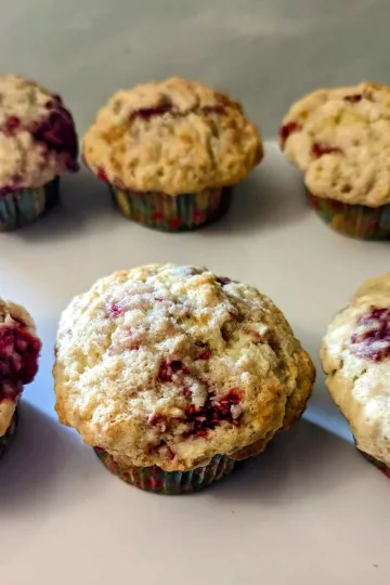 Six raspberry muffins on a plate.
