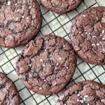 Salted chocolate cookies on a wire rack.