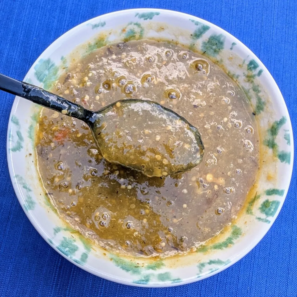 A bowl of tomatillo salsa with a spoon of salsa over the top.