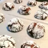 Chocolate crackle cookies on a parchment lined cookie sheet.
