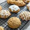 Pumpkin molasses cookies on a cooling rack. Three of the cookies have icing drizzle on them, the others are plain.
