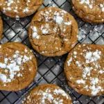 Gingerbread crinkles dusted with powdered sugar on a wire rack.