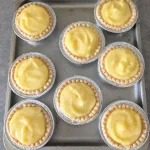 Eight lemon tarts on a tray.