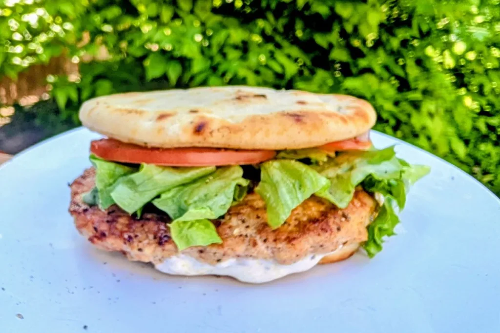 Blackstone Spiced Chicken On Naan sandwich with lettuce, tomato and sauce.