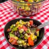 A bowl of Cowboy Caviar on a red and white checkered tablecloth.