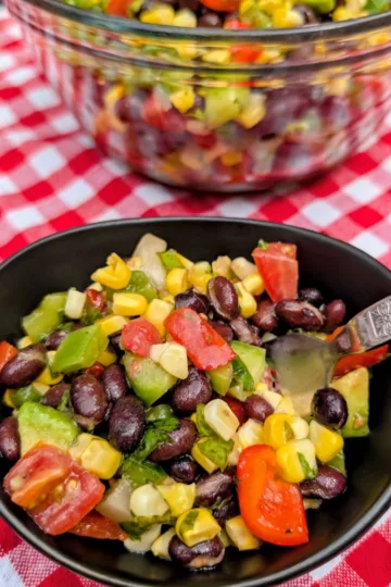 A bowl of Cowboy Caviar on a red and white checkered tablecloth.