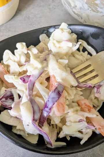 a bowl of honey Dijon coleslaw with a fork.