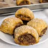 Four Italian Sausage Rolls on a plate with a pan of rolls in the background.