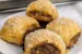 Four Italian Sausage Rolls on a plate with a pan of rolls in the background.